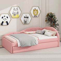 a pink bed sitting in the middle of a bedroom next to a wall with pictures on it