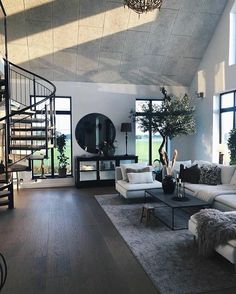 a living room filled with furniture and a spiral staircase in front of large open windows