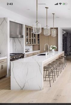 a kitchen with marble counter tops and bar stools next to an open floor plan