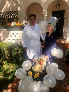 a man and woman standing in front of a balloon arch with a ducky on it