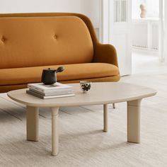 an orange couch and coffee table in a white room with beige carpeted flooring