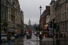 people are walking down the street with umbrellas on a rainy day in london, england