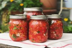 four mason jars filled with tomatoes on top of a table