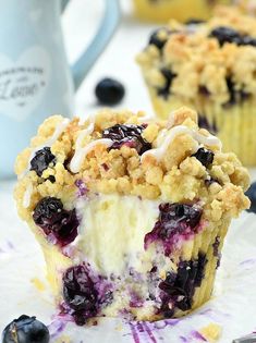 two blueberry crumb muffins are sitting on a paper plate next to a cup of coffee