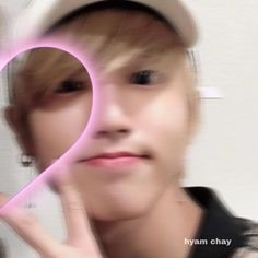 a young man holding up a pink heart shaped object in front of his face and looking at the camera