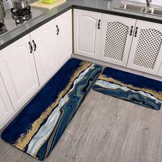 a kitchen with white cabinets and blue area rugs on the floor next to it