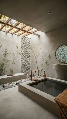 a bathroom with a stone wall and large tub in the center, surrounded by bamboo plants