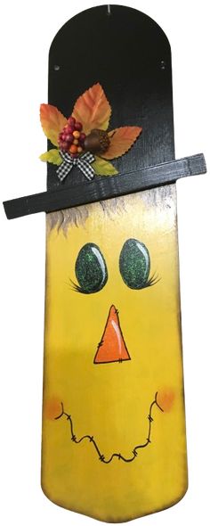 a yellow plastic bag with a face and leaves on it's head, hanging from a metal hook