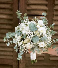 a bridal bouquet with white flowers and greenery