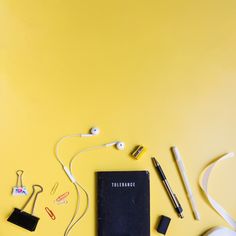 the contents of a cell phone, headphones and ear buds laid out on a yellow background