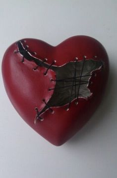 a red heart with a piece of metal in it's center and holes in the middle