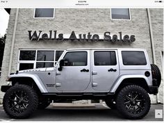 a white jeep parked in front of a building with the words wells auto sales on it