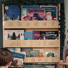 a young boy sitting in front of a bookshelf filled with children's books