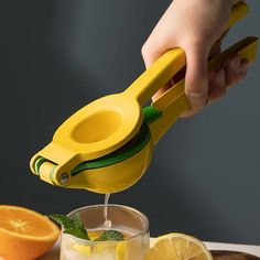 a person is squeezing lemons into a glass with a squeezer on the side