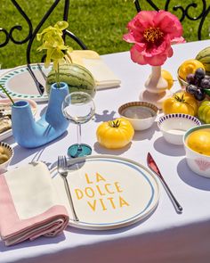 a table set up with plates, bowls and utensils for an outdoor meal