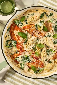 a pasta dish with chicken, spinach and sauce in a pan on a table