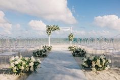 an outdoor wedding set up with white flowers and greenery on the aisle to the beach