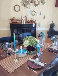 a dining room table is set with place settings and plates, candles, and flowers