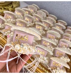 a person is holding up some wedding favors with pearls and ribbons on them in front of other items