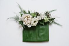 a green bag with white flowers and greenery on the inside is hanging on a wall