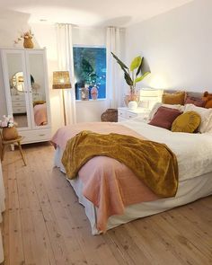 a bedroom with white walls and wooden floors has an orange blanket on the headboard