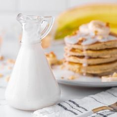 a stack of pancakes sitting on top of a white plate next to a bottle of milk