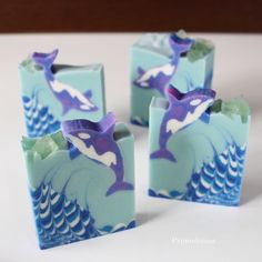 three blue and white soaps with dolphins on them