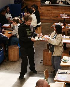 a man standing in front of a group of people sitting at tables with food on them