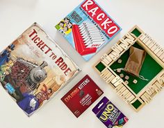 three different games are laid out next to each other on a white surface, including train track and wooden dominos