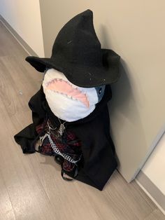 a stuffed animal wearing a black hat and jacket with chains on it's neck