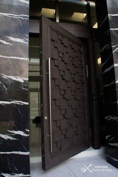 an open door to a building with black marble walls and flooring on the outside