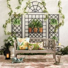 a wooden bench sitting in front of a wall with potted plants