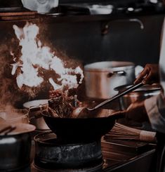 a person cooking food in a wok on top of a stove