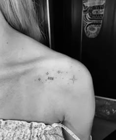 the back of a woman's shoulder with small stars and numbers on it,