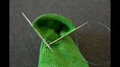 a green knitted bag with needles sticking out of it