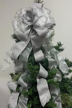 a christmas tree decorated with silver ribbons and bows