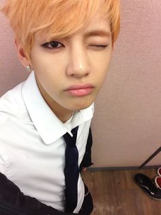 a man with blonde hair wearing a white shirt and black tie, looking at the camera