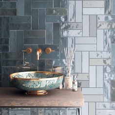 a bowl shaped sink sitting on top of a wooden counter next to a wall mounted faucet