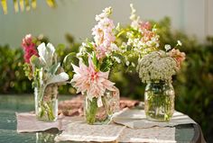 three vases filled with flowers sitting on top of a table