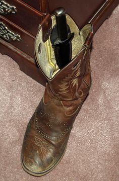 an old pair of cowboy boots is sitting on the floor next to a suitcase and other items