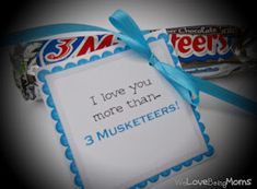 a candy bar with a blue ribbon tied around it and an i love you more than 3 muskers sign