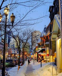 a city street is covered in snow during the winter time, with people walking down it