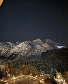 the night sky is lit up over snowy mountains