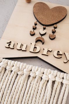 the word aubrey spelled with wooden letters on a piece of wood next to yarn