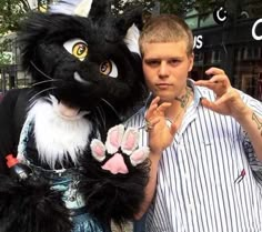 a man standing next to a black and white cat mascot with his hand in the air