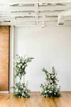 two tall vases filled with flowers on top of a hard wood floor