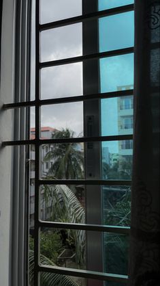 an open window with the view of buildings and palm trees in the distance from outside