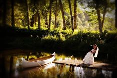 a bride and groom standing on a dock next to canoes