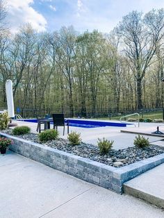 an empty swimming pool in the middle of a park with benches and tables around it