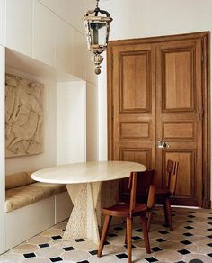 a dining room table with two chairs and a bench in front of a wooden door